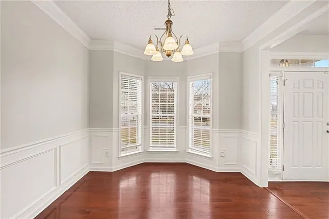 a view of an empty room with wooden floor and windows