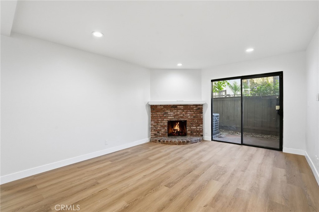 15511 Sherman Way, Unit 19 Van Nuys, CA 91406 - Photo 5 of 31 a view of an empty room with wooden floor fireplace and a window