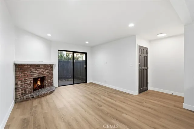a view of an empty room with wooden floor fireplace and a window