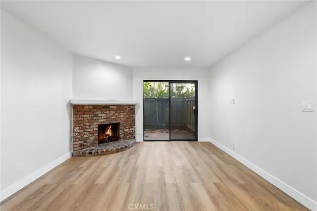 an empty room with wooden floor fireplace and windows