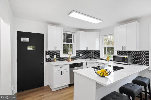 a kitchen with sink a stove and chairs with wooden floor