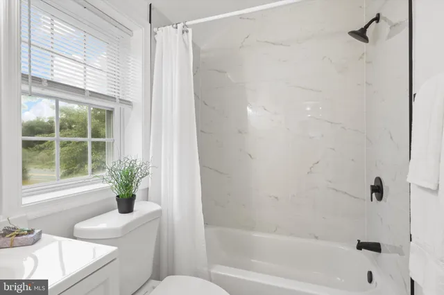 a bathroom with a shower curtain a window and a sink