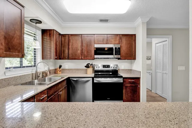 a kitchen with stainless steel appliances a sink a stove a microwave a sink a refrigerator and cabinets