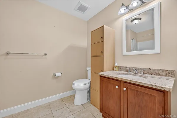 a bathroom with a granite countertop sink a toilet and a mirror