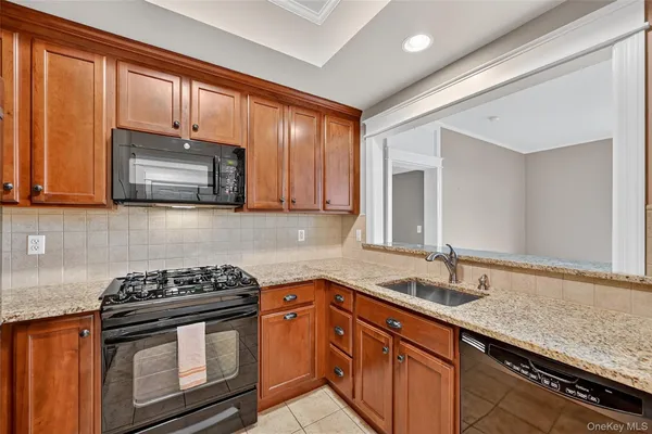 a kitchen with granite countertop stainless steel appliances a stove sink and cabinets