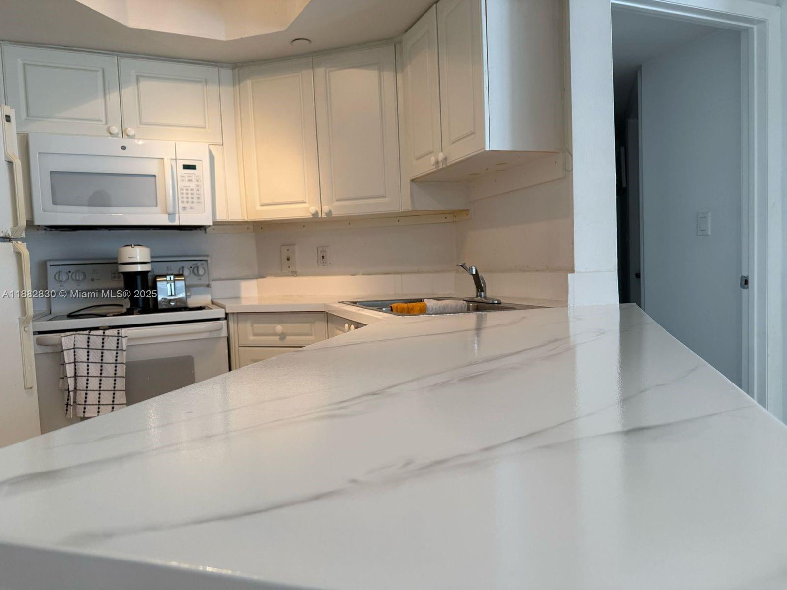 8911 Collins Avenue, Unit 203 Surfside, FL 33154 - Photo 1 of 10 a kitchen with granite countertop a sink a stove and cabinets