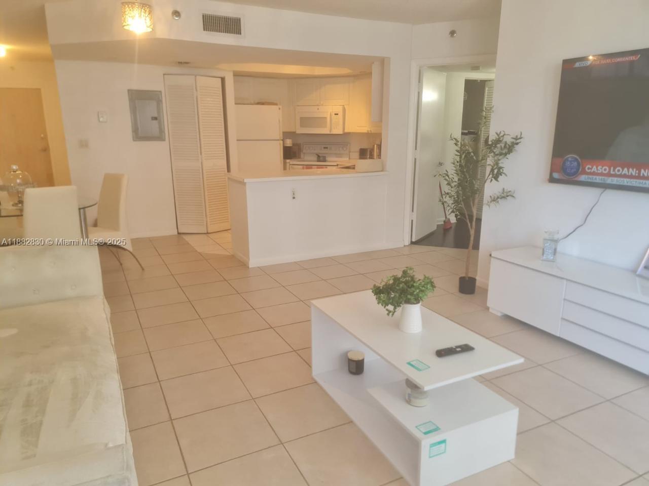 8911 Collins Avenue, Unit 203 Surfside, FL 33154 - Photo 2 of 10 a living room with furniture and a flat screen tv