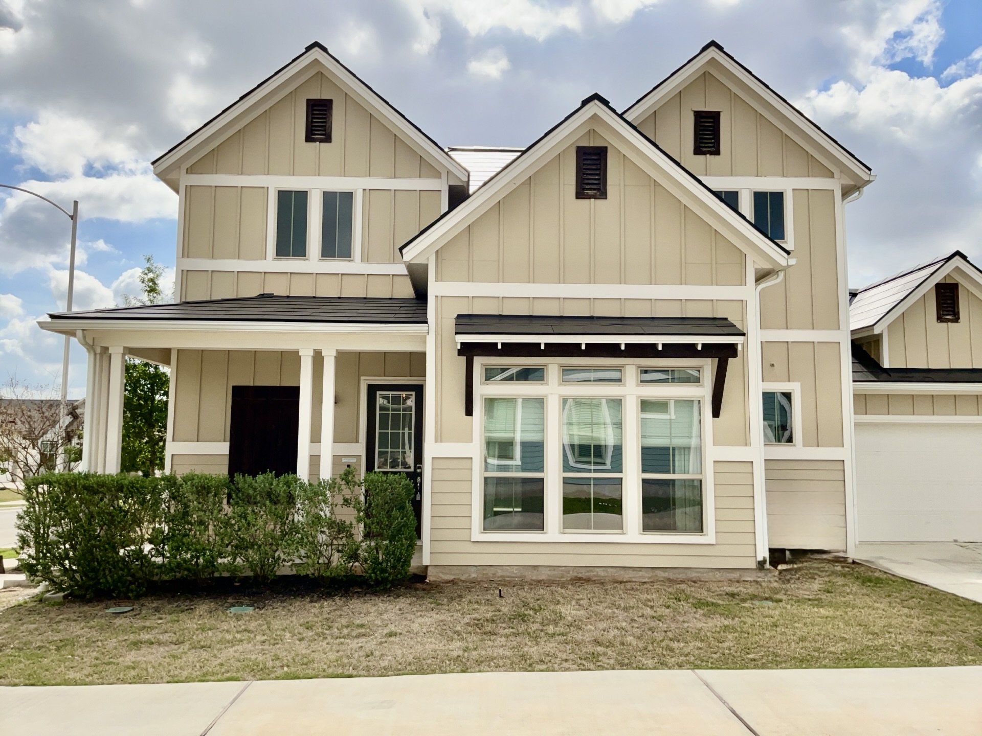 8315 Laughlin Lane Austin, TX 78744 - Photo 2 of 23 Craftsman house featuring board and batten siding, covered porch, an attached garage, and driveway