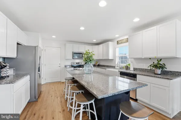 a kitchen with granite countertop kitchen island white cabinets and stainless steel appliances