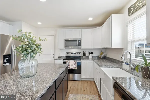 a kitchen with stainless steel appliances granite countertop a sink a stove top oven a counter space and cabinets