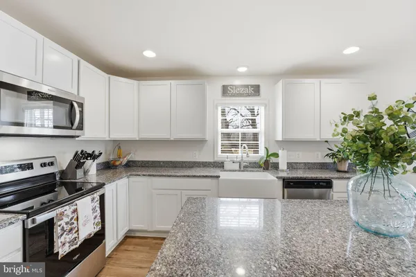 a kitchen with granite countertop a stove a sink and a microwave
