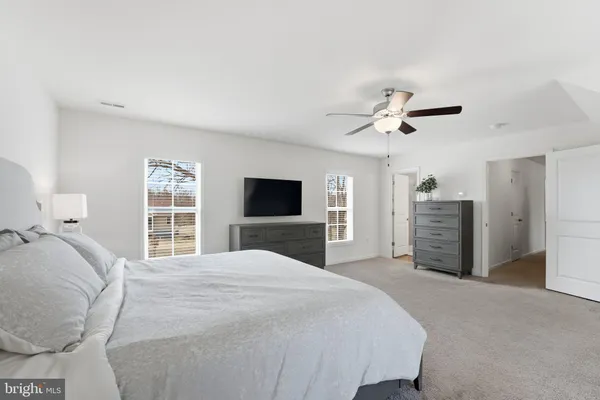 a spacious bedroom with a large bed a chandelier and a flat tv screen