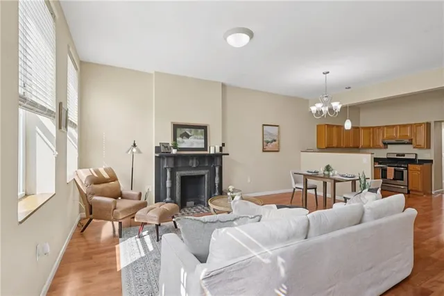 a kitchen with stainless steel appliances granite countertop a stove top oven a sink a dining table and chairs with wooden floor