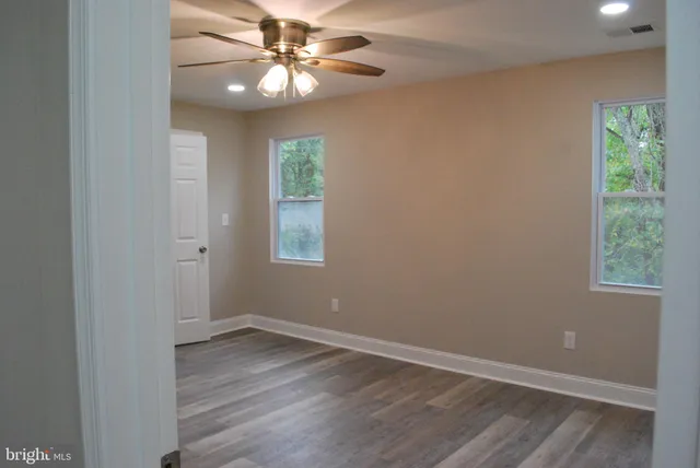 an empty room with wooden floor closet and windows