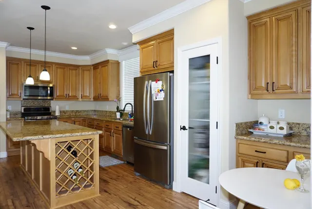 a kitchen with stainless steel appliances granite countertop a refrigerator a stove and a sink with wooden floor