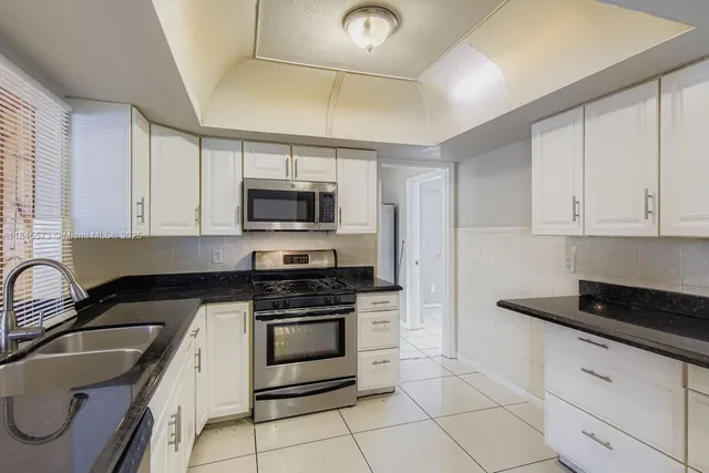 a kitchen with granite countertop white cabinets stainless steel appliances and a sink