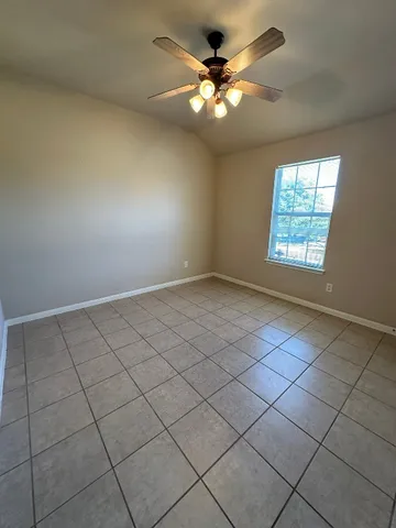 an empty room with windows and ceiling fan
