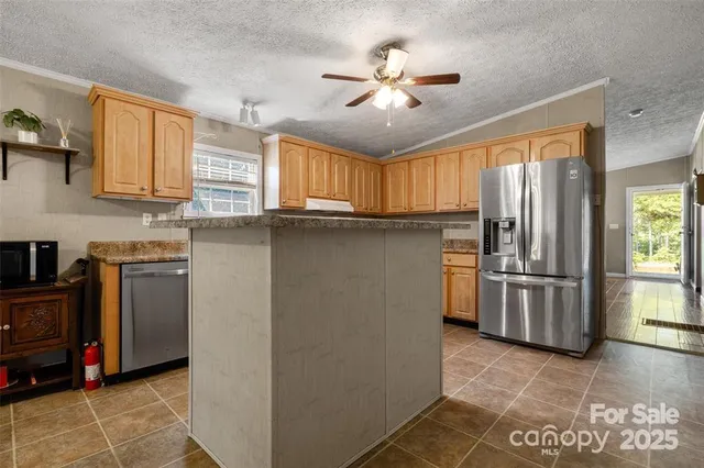 a kitchen with stainless steel appliances granite countertop a refrigerator a stove a sink and dishwasher with wooden cabinet
