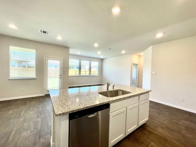 a kitchen with granite countertop a sink and dishwasher with wooden floor