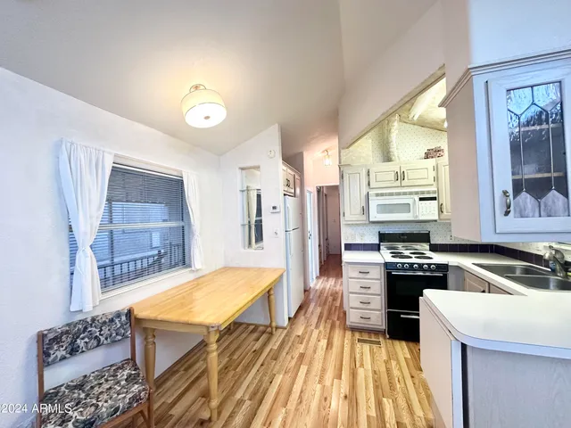 a living room with stainless steel appliances furniture a rug and a kitchen view