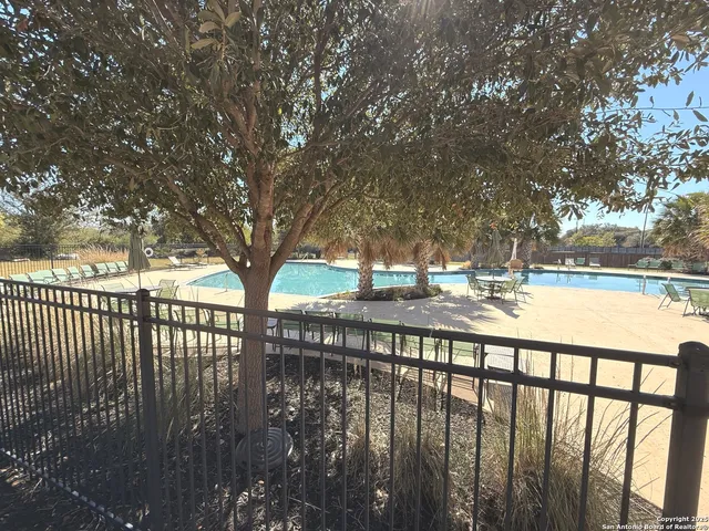 a view of swimming pool with lawn chairs and plants
