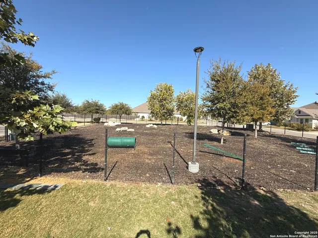 a view of pool with lawn chairs and large trees