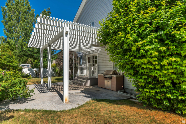 546 Wheatridge Road Tooele, UT 84074 - Photo 5 of 49 Exterior patio featuring a white pergola structure over stamped concrete pavers w/ barbeque