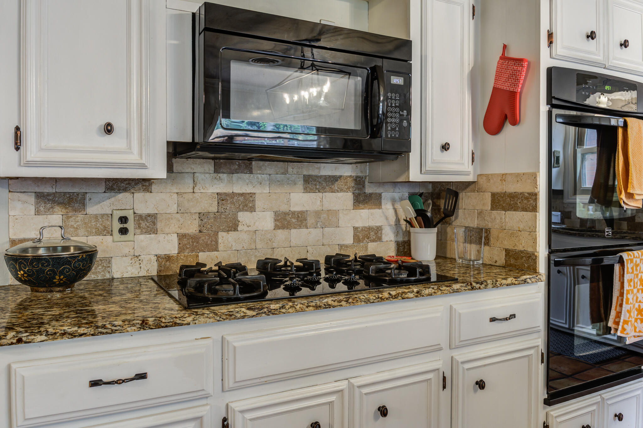 3420 60th Street Lubbock, TX 79413 - Photo 29 of 57 a kitchen with white cabinets a stove and a microwave
