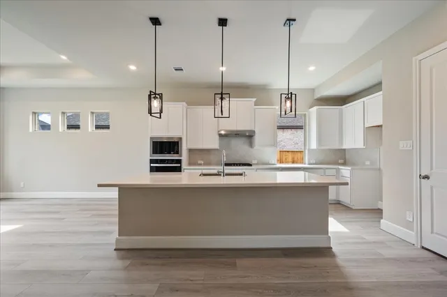 a large kitchen with a center island wooden floor and a counter top space