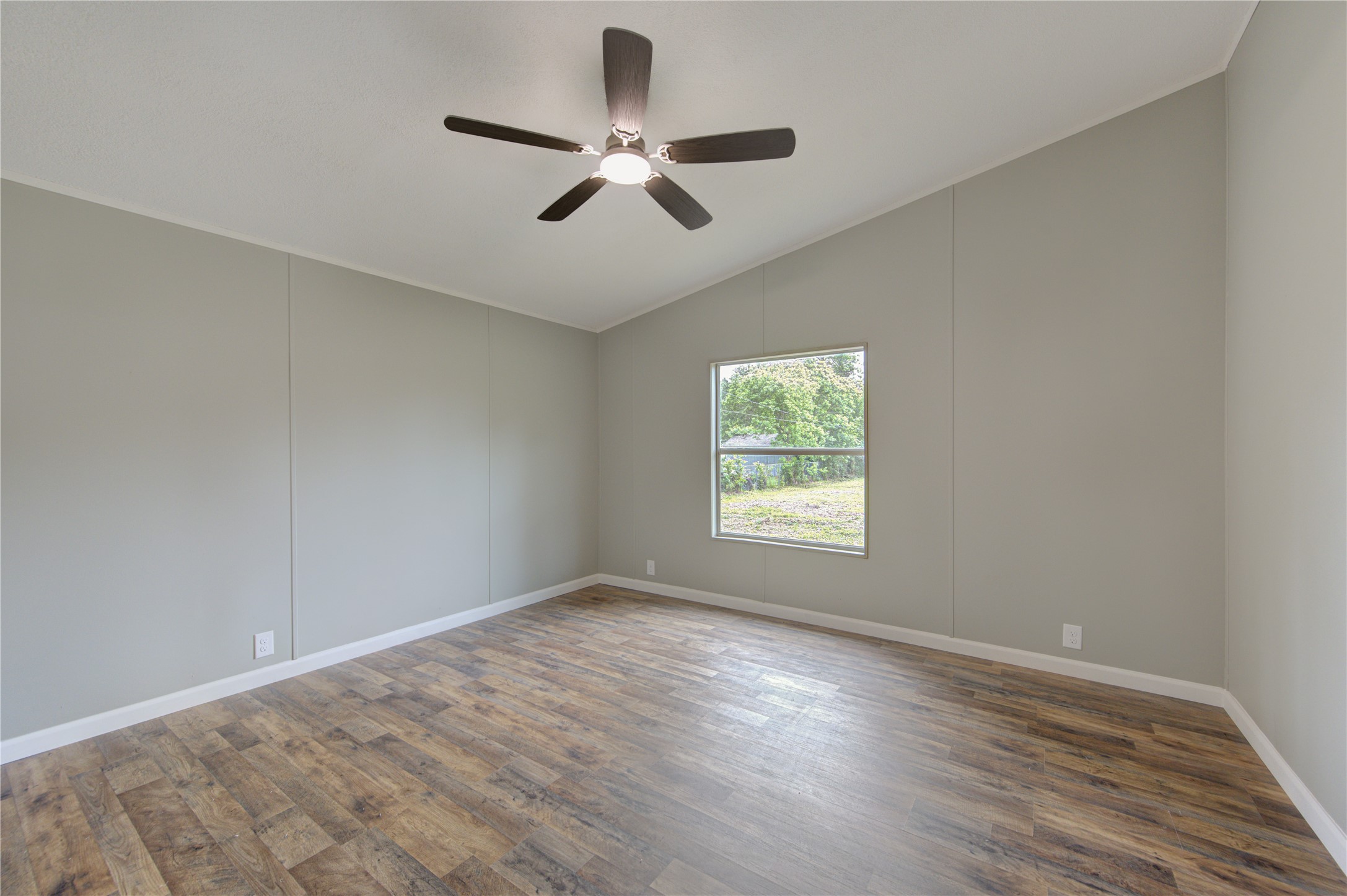30226 Davis Street Magnolia, TX 77355 - Photo 37 of 50 This room features neutral walls, wood flooring, and a ceiling fan. A large window provides natural light with a view of the greenery outside.