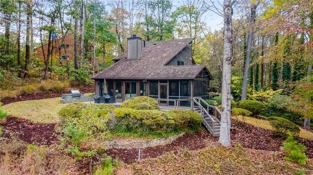 a view of a house with a yard and large trees