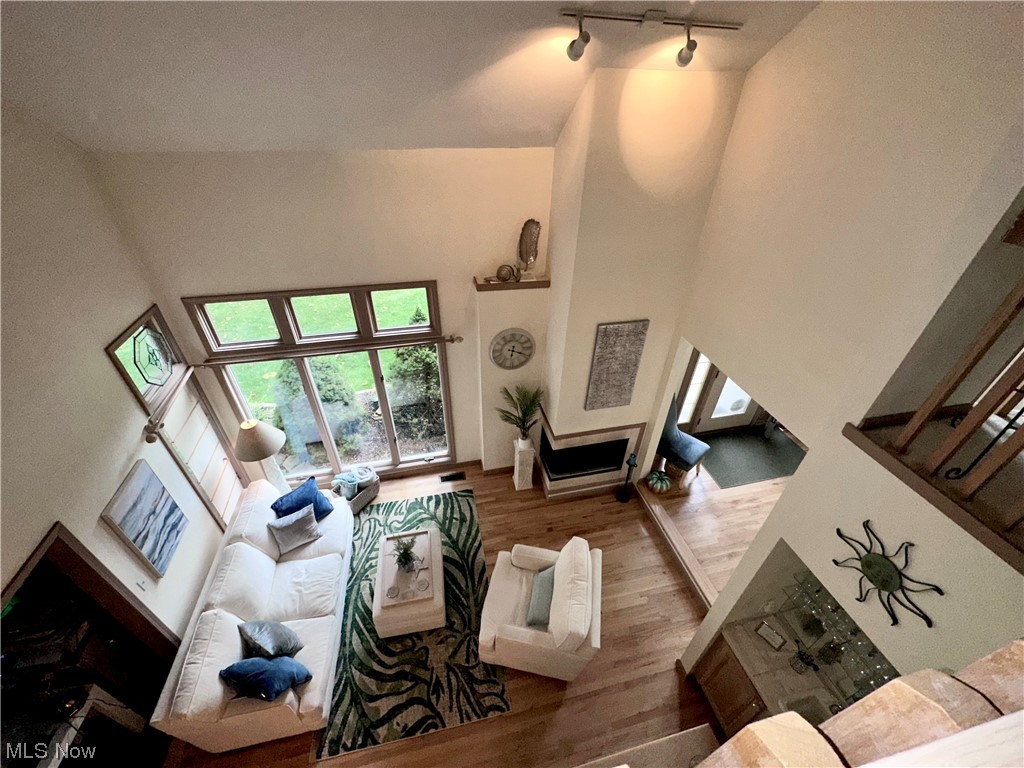 7262 Stone Road Independence, OH 44131 - Photo 11 of 34 Living room with rail lighting, vaulted ceiling, a high ceiling, and wood-type flooring