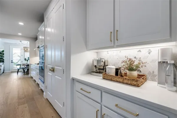 a hallway with white cabinets and wooden floor