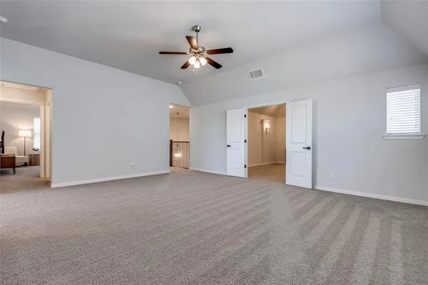 a view of an empty room with chandelier fan