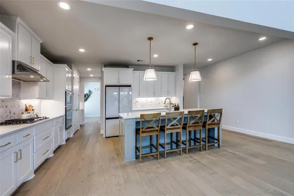 a kitchen with kitchen island a dining table chairs stainless steel appliances and cabinets