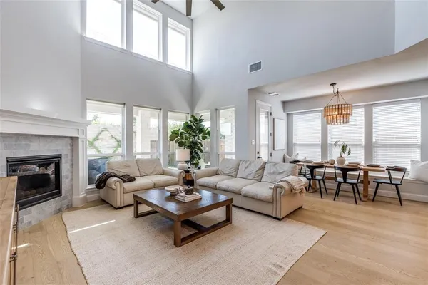 a living room with furniture potted plant floor to ceiling windows and a fireplace