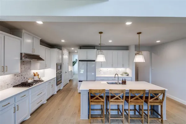 a kitchen with a dining table chairs sink and white cabinets