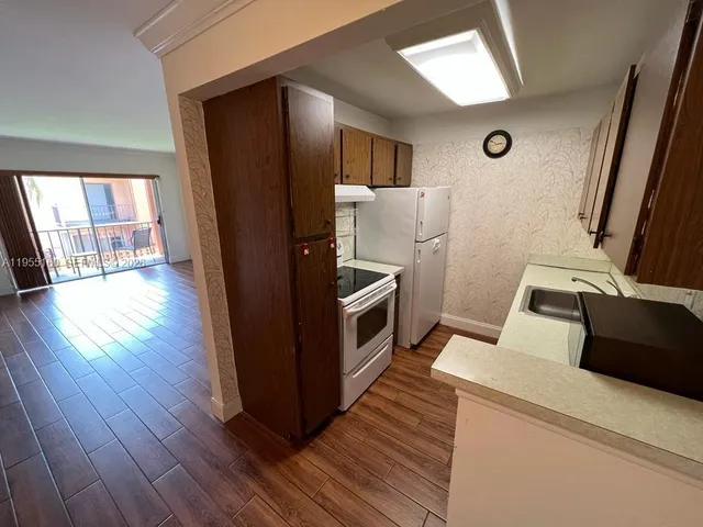 a kitchen with a refrigerator and wooden floor