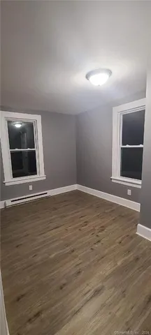a view of an empty room with wooden floor and cabinet