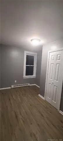 an empty room with wooden floor and mirror