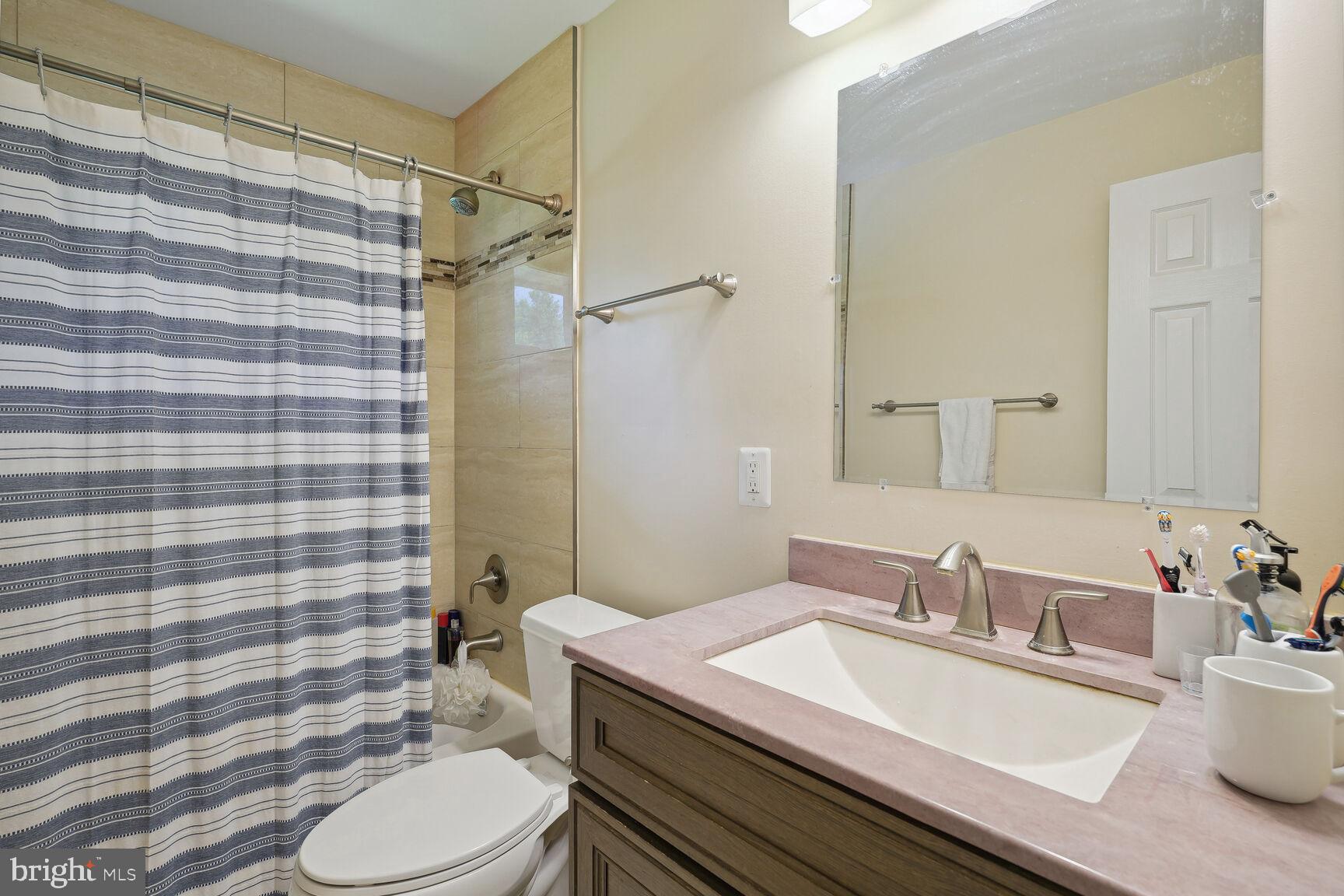 7011 Hector Road McLean, VA 22101 - Photo 13 of 20 a bathroom with a granite countertop sink toilet a mirror and shower curtain