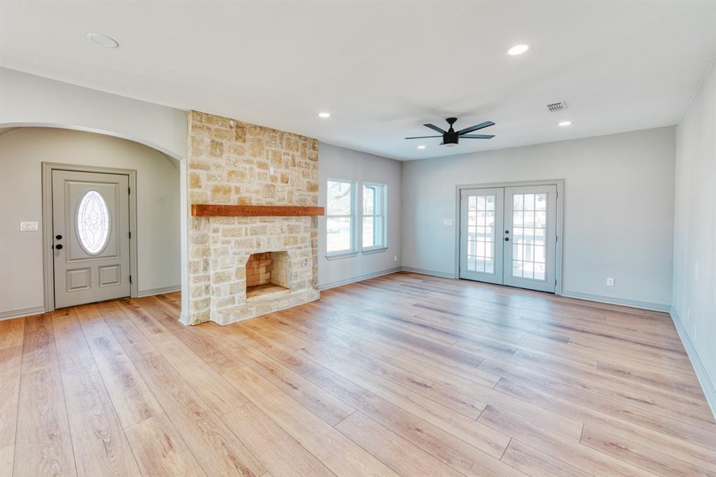 808 North Main Street Tioga, TX 76271 - Photo 6 of 23 an empty room with wooden floor fireplace and windows