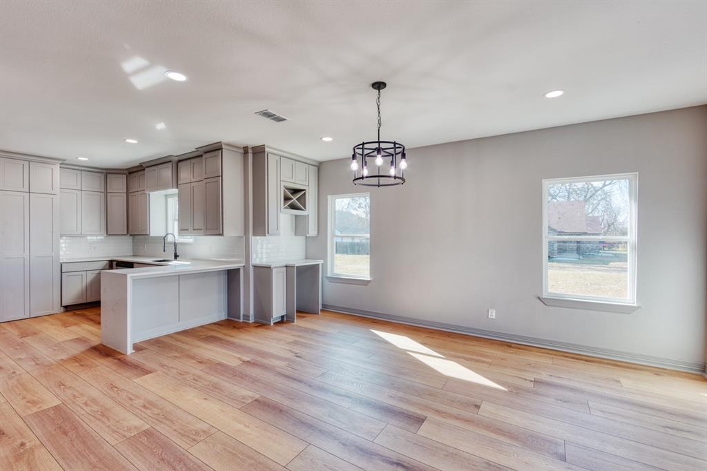 808 North Main Street Tioga, TX 76271 - Photo 10 of 23 a large kitchen with kitchen island a refrigerator a sink dishwasher a stove and white countertops with wooden floor