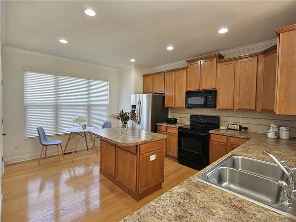 a kitchen with kitchen island granite countertop a sink cabinets and wooden floor
