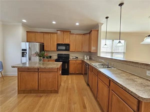 a kitchen with kitchen island granite countertop a sink a counter top space appliances and cabinets