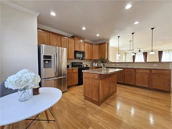 a kitchen with stainless steel appliances granite countertop a sink dishwasher a refrigerator with white cabinets and wooden floor