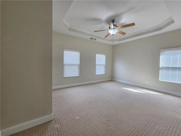 an empty room with windows and ceiling fan