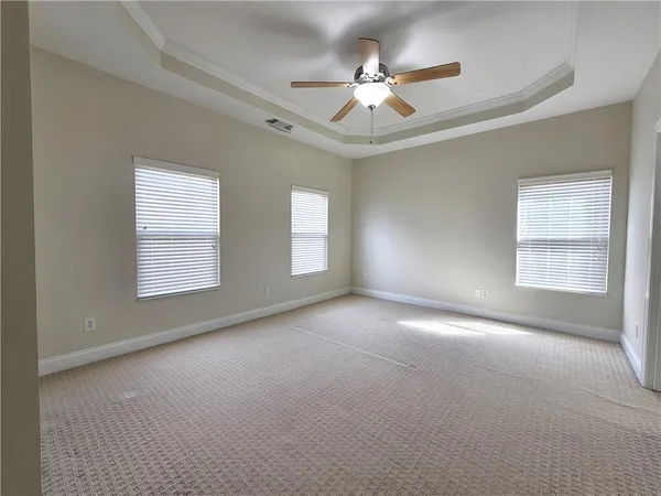 an empty room with windows and fan
