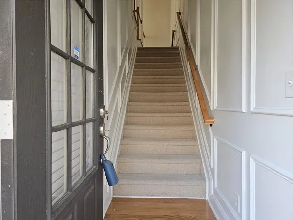 a view of staircase with wooden floor and lots of frames on wall