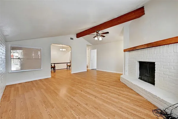 a view of empty room with wooden floor and fireplace